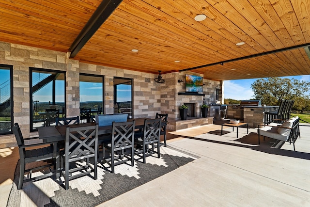 view of patio / terrace featuring exterior bar, an outdoor stone fireplace, and exterior kitchen