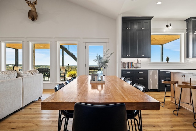 dining area with light wood-type flooring, a wealth of natural light, and lofted ceiling