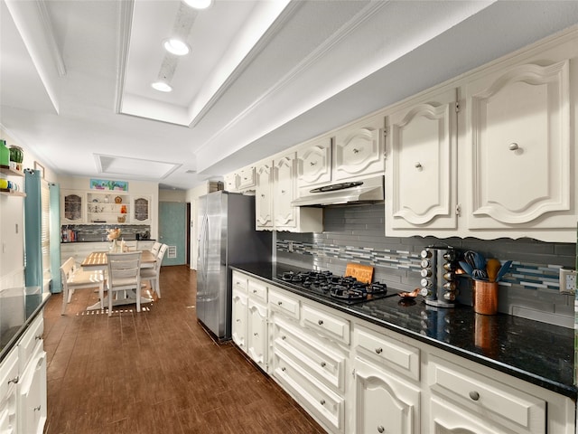 kitchen with dark wood-type flooring, black gas cooktop, decorative backsplash, stainless steel fridge, and white cabinetry