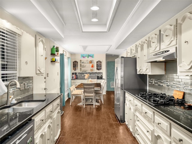 kitchen featuring dark wood-type flooring, black gas stovetop, sink, stainless steel dishwasher, and a tray ceiling