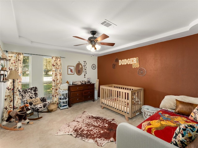 carpeted bedroom with a tray ceiling and ceiling fan