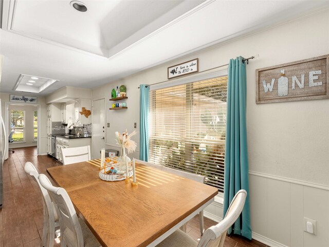 dining room with dark wood-type flooring and a tray ceiling