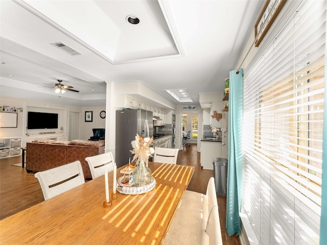 dining space featuring a raised ceiling, ceiling fan, and hardwood / wood-style flooring