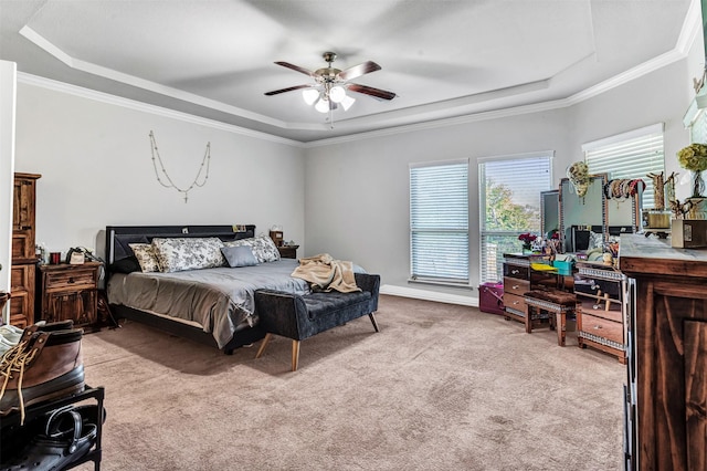 carpeted bedroom featuring a raised ceiling, ceiling fan, crown molding, and connected bathroom