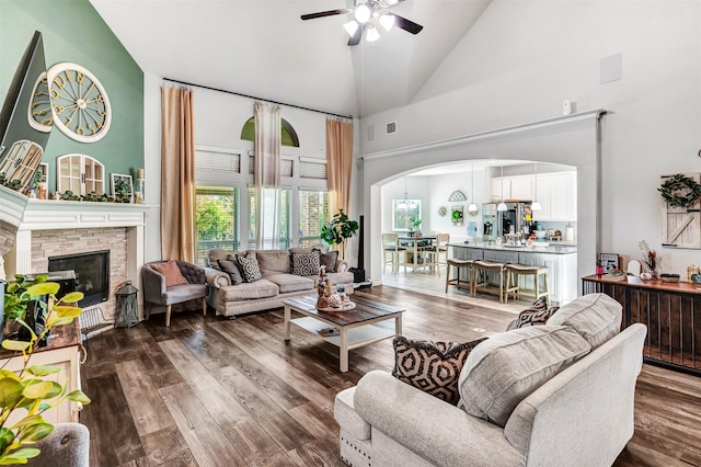 living room featuring ceiling fan, hardwood / wood-style floors, high vaulted ceiling, and a fireplace