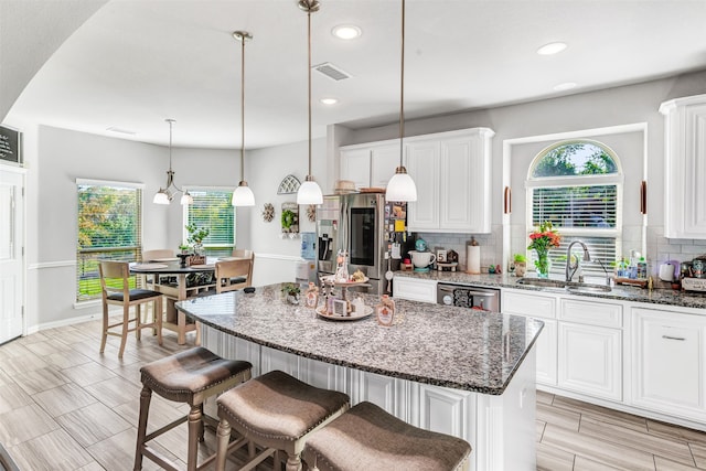 kitchen featuring sink, white cabinets, a center island, and dark stone countertops