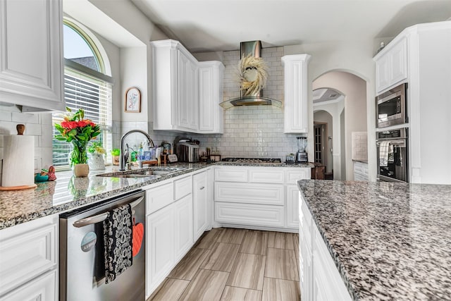 kitchen with appliances with stainless steel finishes, white cabinets, backsplash, and dark stone countertops