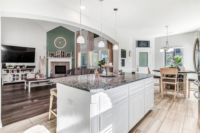 kitchen featuring decorative light fixtures, a center island, dark stone countertops, and white cabinetry