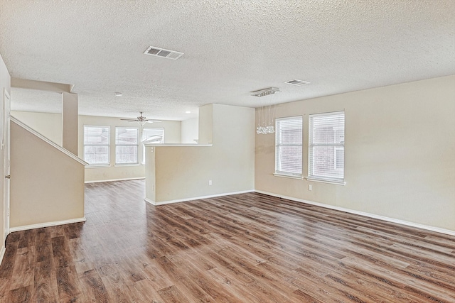 unfurnished living room featuring ceiling fan, wood-type flooring, a textured ceiling, and a wealth of natural light