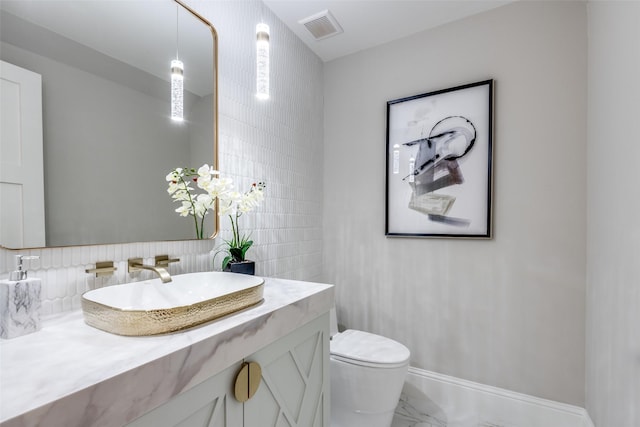 bathroom featuring vanity, toilet, and tile walls