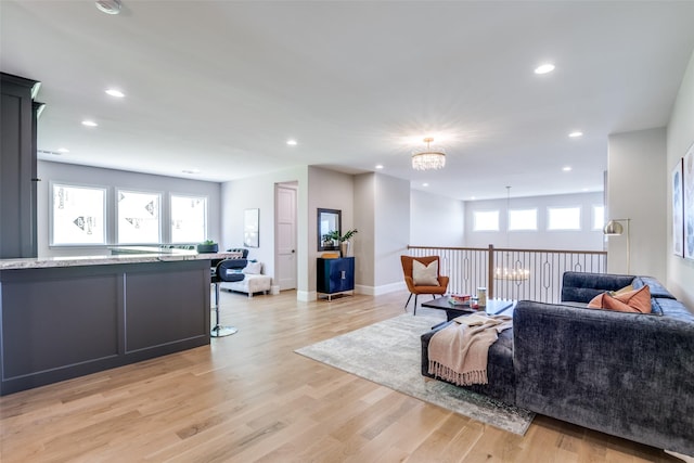 living room with plenty of natural light, a notable chandelier, and light wood-type flooring