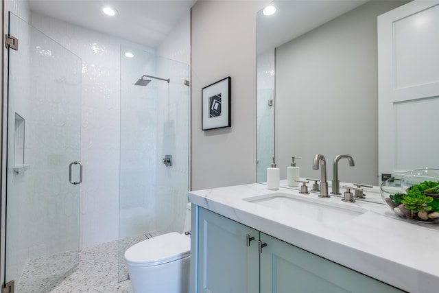 bathroom featuring vanity, toilet, and a shower with door