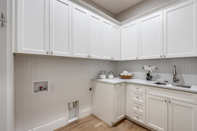 washroom featuring sink, cabinets, hookup for an electric dryer, hookup for a washing machine, and light hardwood / wood-style floors