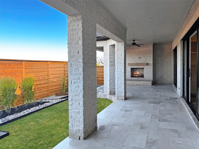 view of patio / terrace with an outdoor stone fireplace and ceiling fan