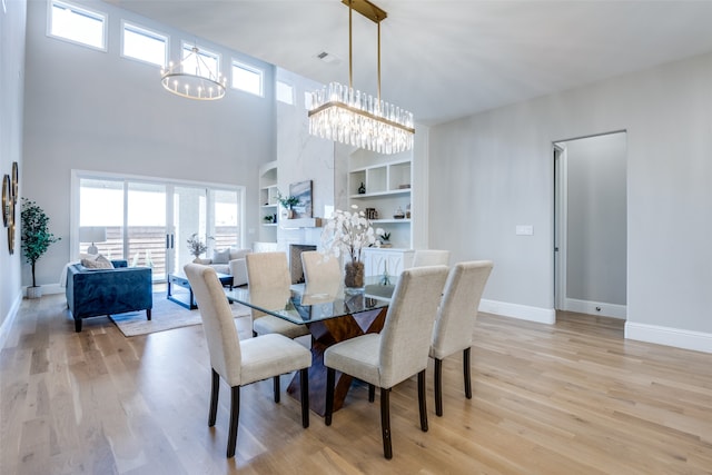 dining room with built in shelves, a healthy amount of sunlight, light wood-type flooring, and a chandelier