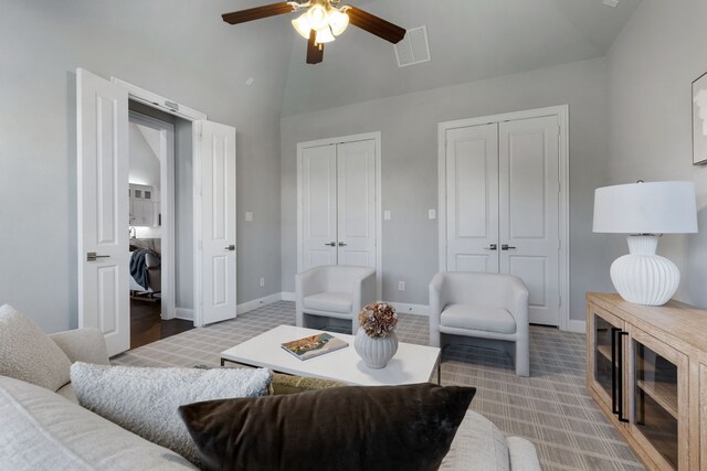 living room featuring ceiling fan, light carpet, and lofted ceiling