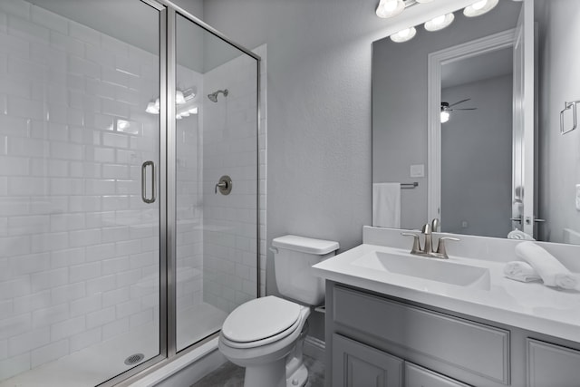 bathroom with ceiling fan, a shower with door, vanity, and toilet