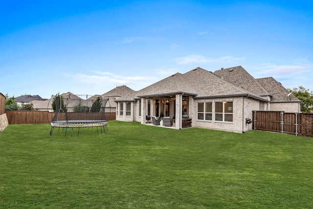 back of property with a yard and a trampoline