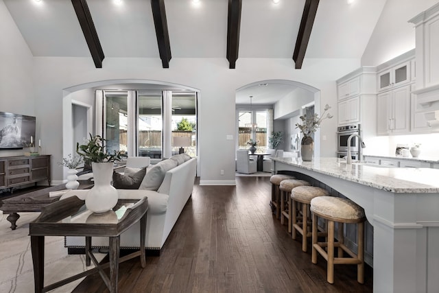 living room with a chandelier, lofted ceiling with beams, and dark wood-type flooring