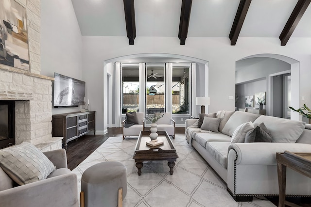 living room featuring a fireplace, vaulted ceiling with beams, and light wood-type flooring