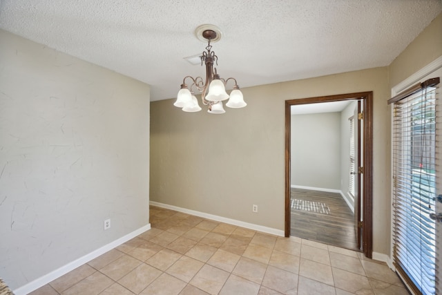 unfurnished room featuring a textured ceiling, light hardwood / wood-style flooring, and a notable chandelier