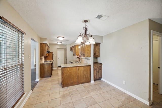 kitchen featuring a textured ceiling, a notable chandelier, sink, and hanging light fixtures