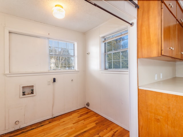 washroom with cabinets, hookup for a washing machine, ornamental molding, a textured ceiling, and light hardwood / wood-style floors