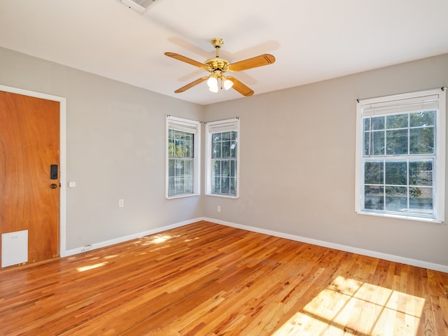 spare room with ceiling fan, light wood-type flooring, and a wealth of natural light