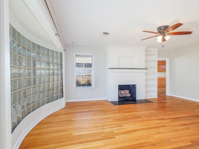 unfurnished living room with a fireplace, light wood-type flooring, and ceiling fan