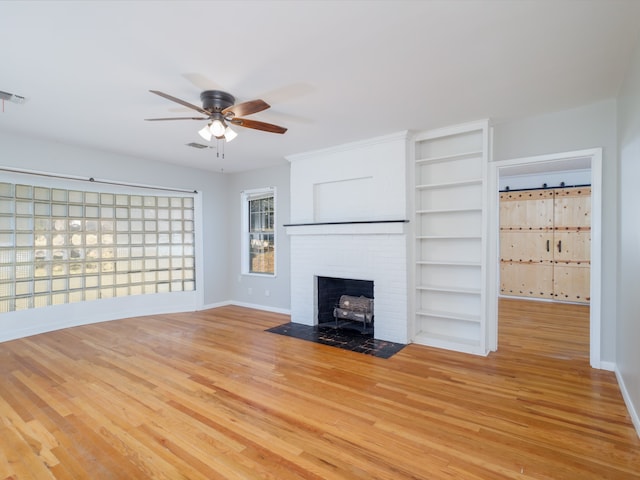 unfurnished living room featuring a fireplace, light hardwood / wood-style flooring, and ceiling fan