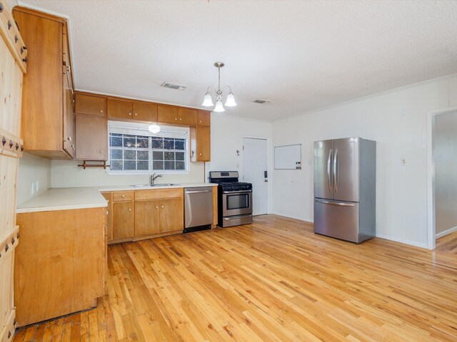 kitchen with decorative light fixtures, ornamental molding, appliances with stainless steel finishes, a notable chandelier, and light hardwood / wood-style floors