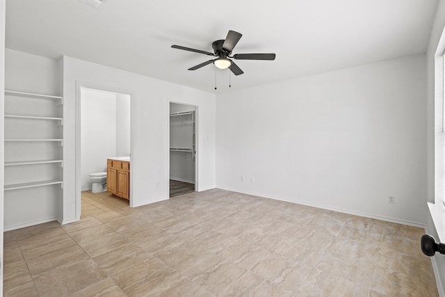 unfurnished bedroom featuring ensuite bath, ceiling fan, a closet, and a walk in closet