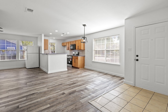 kitchen with stainless steel electric stove, white refrigerator, hanging light fixtures, light wood-type flooring, and kitchen peninsula