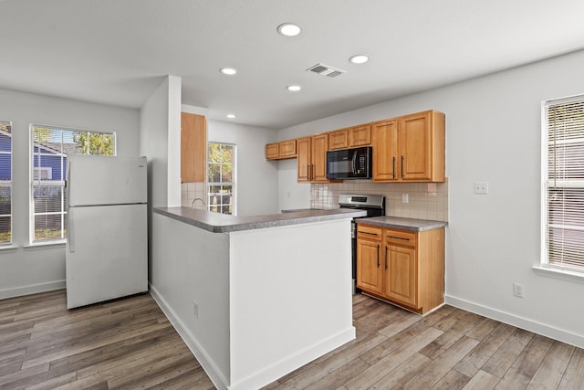 kitchen featuring white refrigerator, stainless steel stove, a wealth of natural light, and light hardwood / wood-style floors