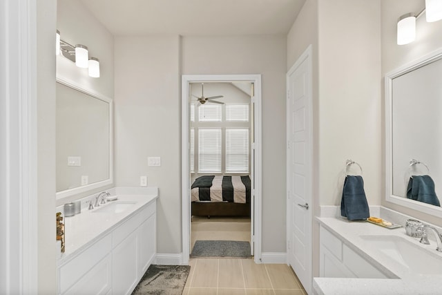 ensuite bathroom with tile patterned flooring, two vanities, baseboards, and a sink