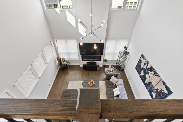 living room with a notable chandelier, a high ceiling, baseboards, and wood finished floors