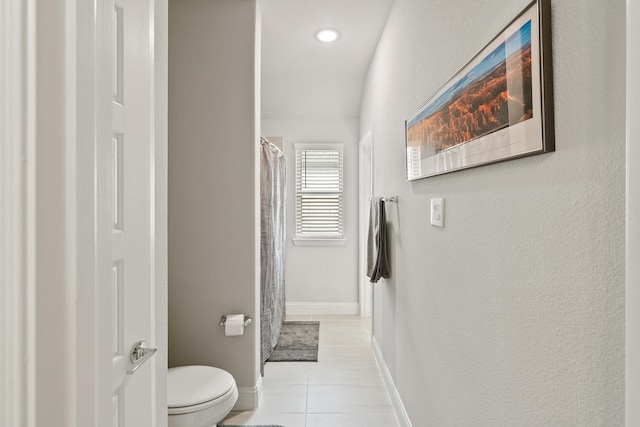 full bathroom with curtained shower, tile patterned floors, toilet, and baseboards