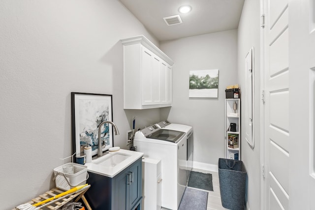 washroom with visible vents, washing machine and dryer, tile patterned floors, cabinet space, and a sink