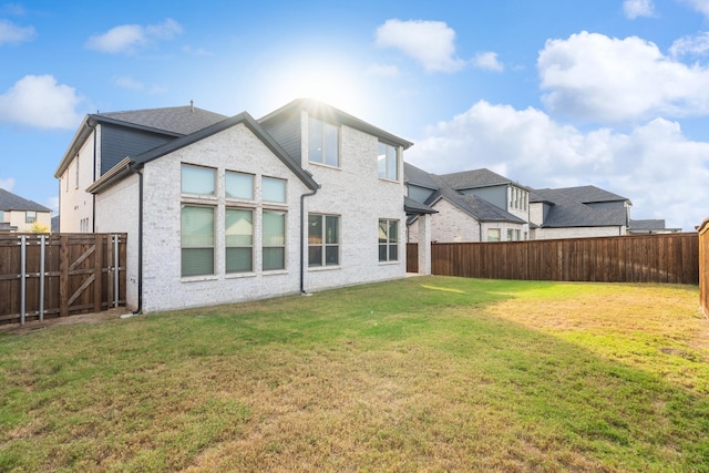 back of property featuring a yard, brick siding, and a fenced backyard