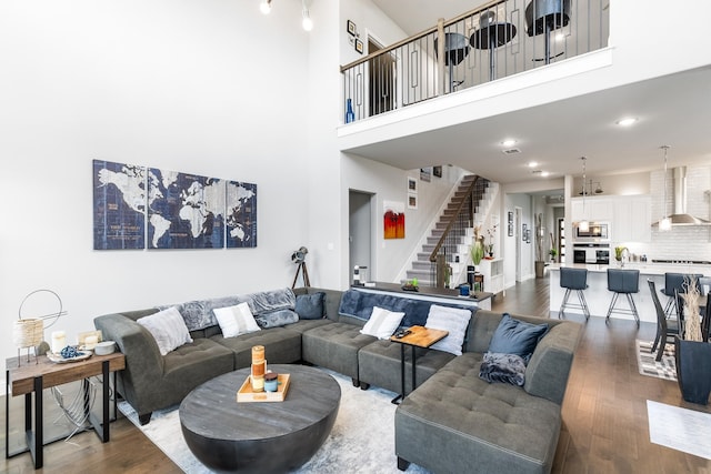 living room with stairs, wood finished floors, and a towering ceiling