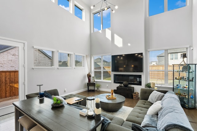 living area with baseboards, a high ceiling, and wood finished floors