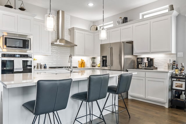 kitchen featuring dark wood finished floors, light countertops, wall chimney exhaust hood, and stainless steel appliances