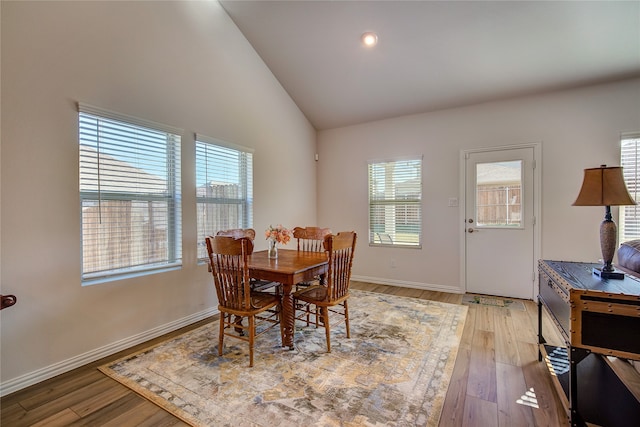 dining room with hardwood / wood-style floors, high vaulted ceiling, and a wealth of natural light