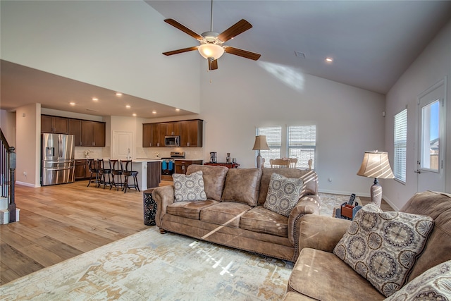 living room featuring ceiling fan, a healthy amount of sunlight, light wood-type flooring, and high vaulted ceiling