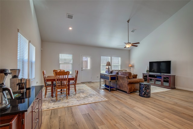 living room with ceiling fan, light wood-type flooring, and high vaulted ceiling