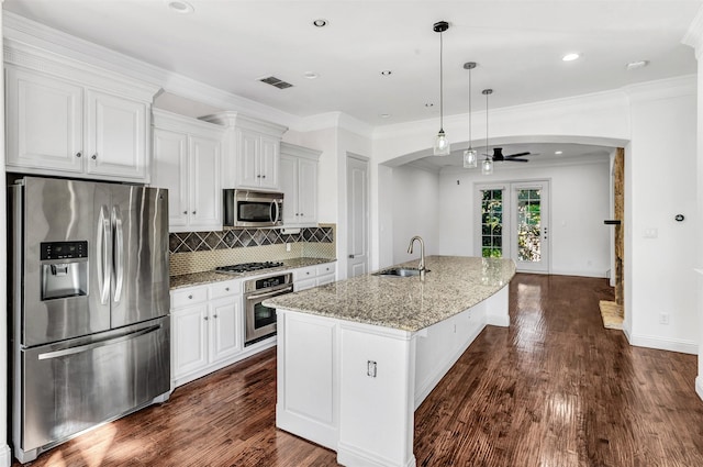 kitchen featuring appliances with stainless steel finishes, white cabinetry, an island with sink, sink, and light stone countertops