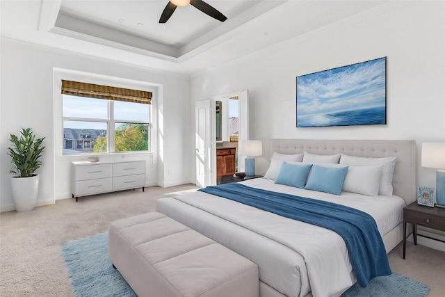 bedroom featuring a raised ceiling, crown molding, and light carpet