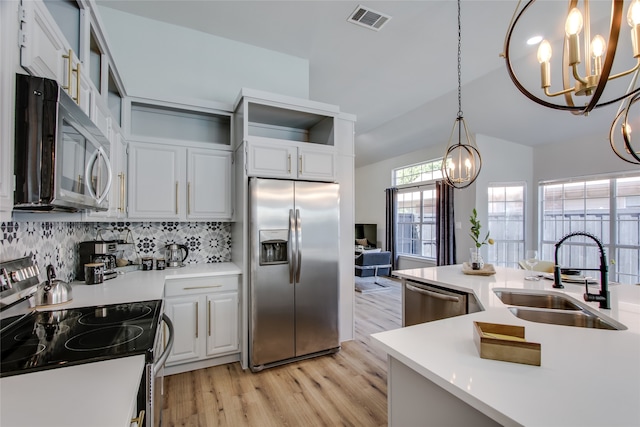 kitchen with sink, backsplash, light hardwood / wood-style floors, decorative light fixtures, and appliances with stainless steel finishes