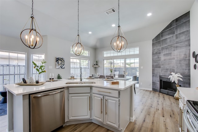 kitchen featuring a healthy amount of sunlight, stainless steel appliances, a center island with sink, and light hardwood / wood-style floors