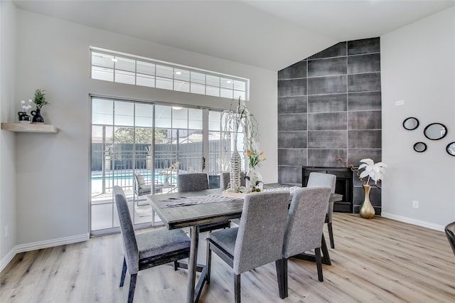 dining area with light hardwood / wood-style floors, tile walls, and vaulted ceiling